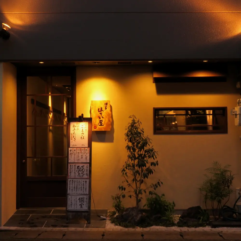 夜の冷泉町店。塗り壁と格子戸に、やわらかな明かり